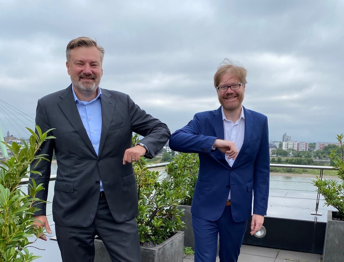 Dr. Thomas Schönemeier, Managing Partner der ConVista Consulting AG und Eric Chall, Geschäftsführer der novaCapta GmbH auf einer Dachterrasse mit dem Fluss Rhein im Hintergrund