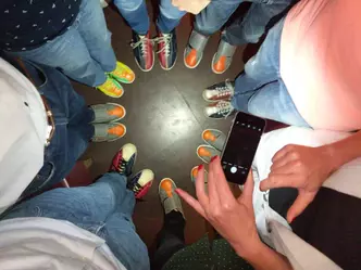 Blick von oben auf einen Kreis von Personen ab der Hüfte bis zu den Füßen auf dem alle Bowlingschuhe tragen