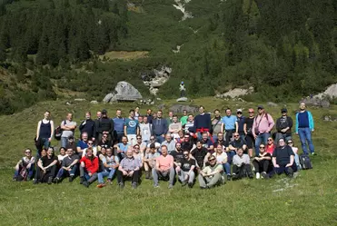 Gruppenfoto der Mitarbeitenden auf einer Wiese in den Bergen im Rahmen einer Team Reise