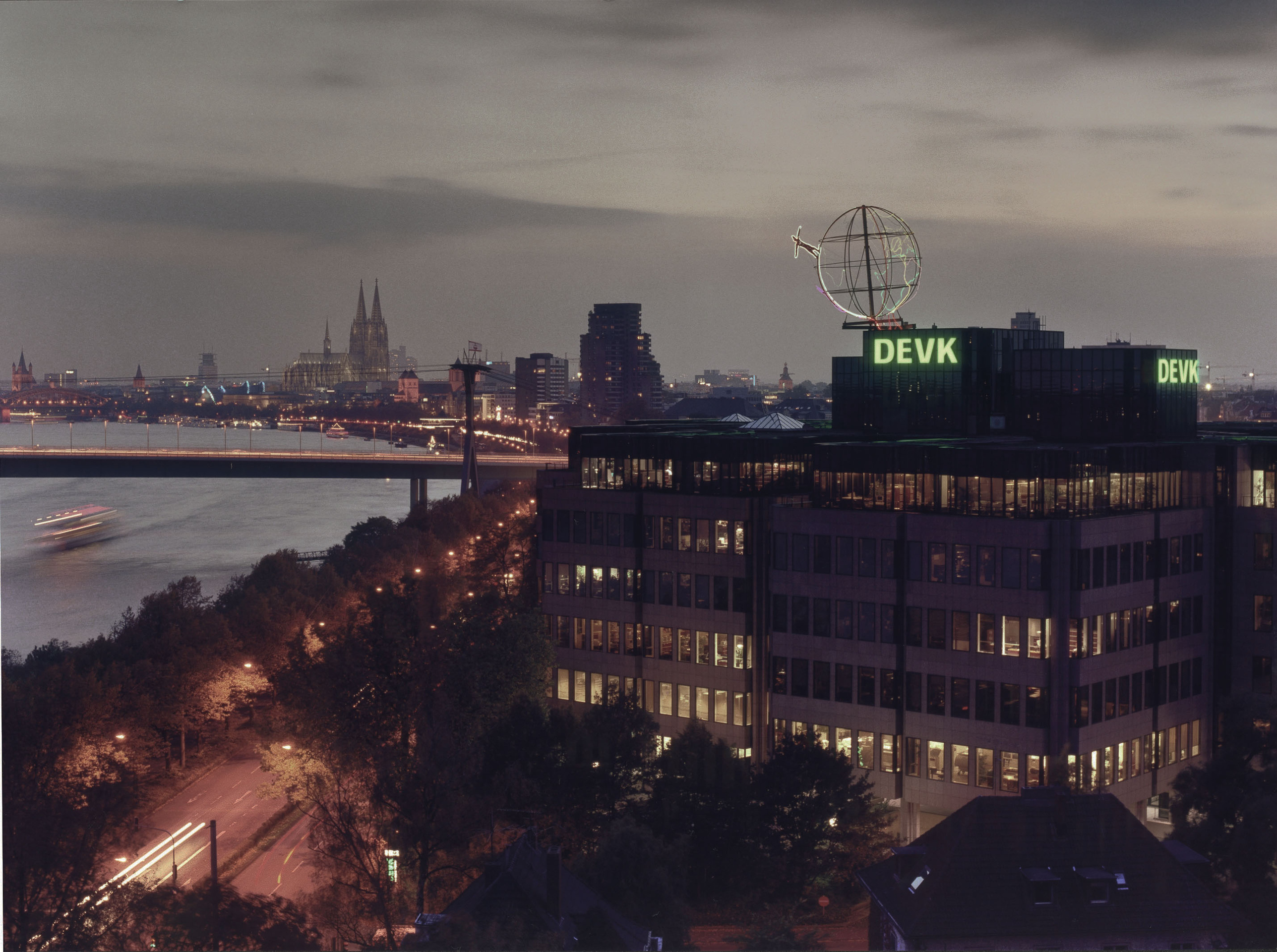 Foto der Firmenzentrale der DEVK mit Kölner Skyline im Hintergrund im Abendlicht